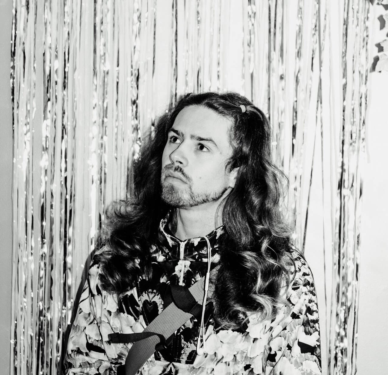 a bearded man with curly long hair looking up in the distance